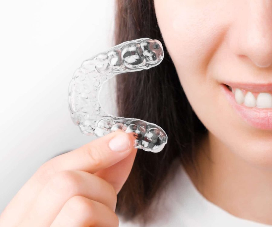 Close up woman holding a transparent removable braces for perfect smile. Orthodontic aligners for straightening and whitening teeth